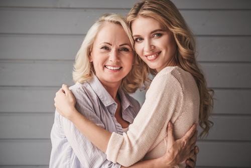 Mother and daughter embracing each other and smiling
