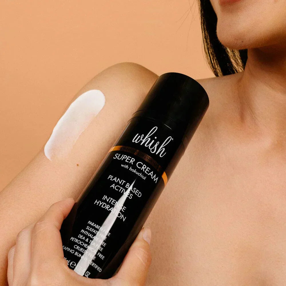 A person applies Whish Super Cream with Bakuchiol to their arm, showing the lotion’s texture.