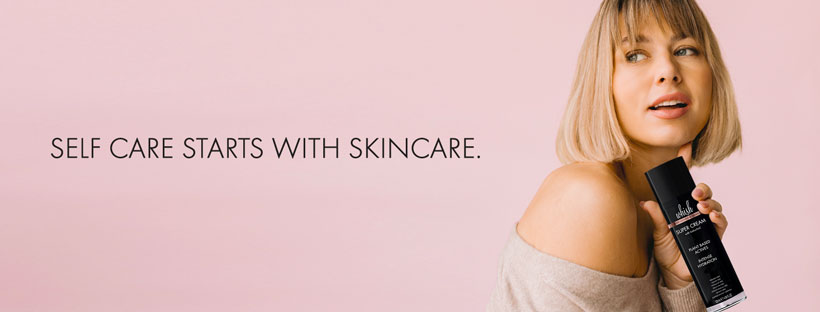 Woman holding Whish Beauty Super Cream against a pink background with the message “Self care starts with skincare.”