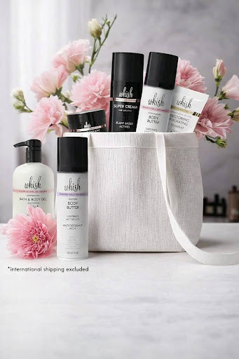 Whish Beauty skincare gift set with body care products arranged in a fabric bag and pink flowers.